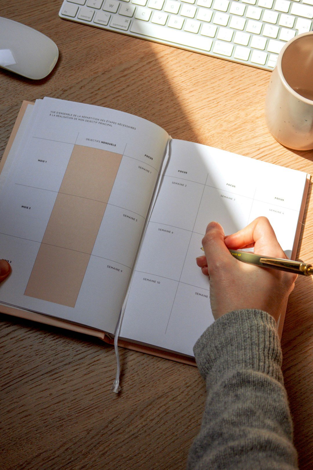 Hands writing business notes in a planner on a desk